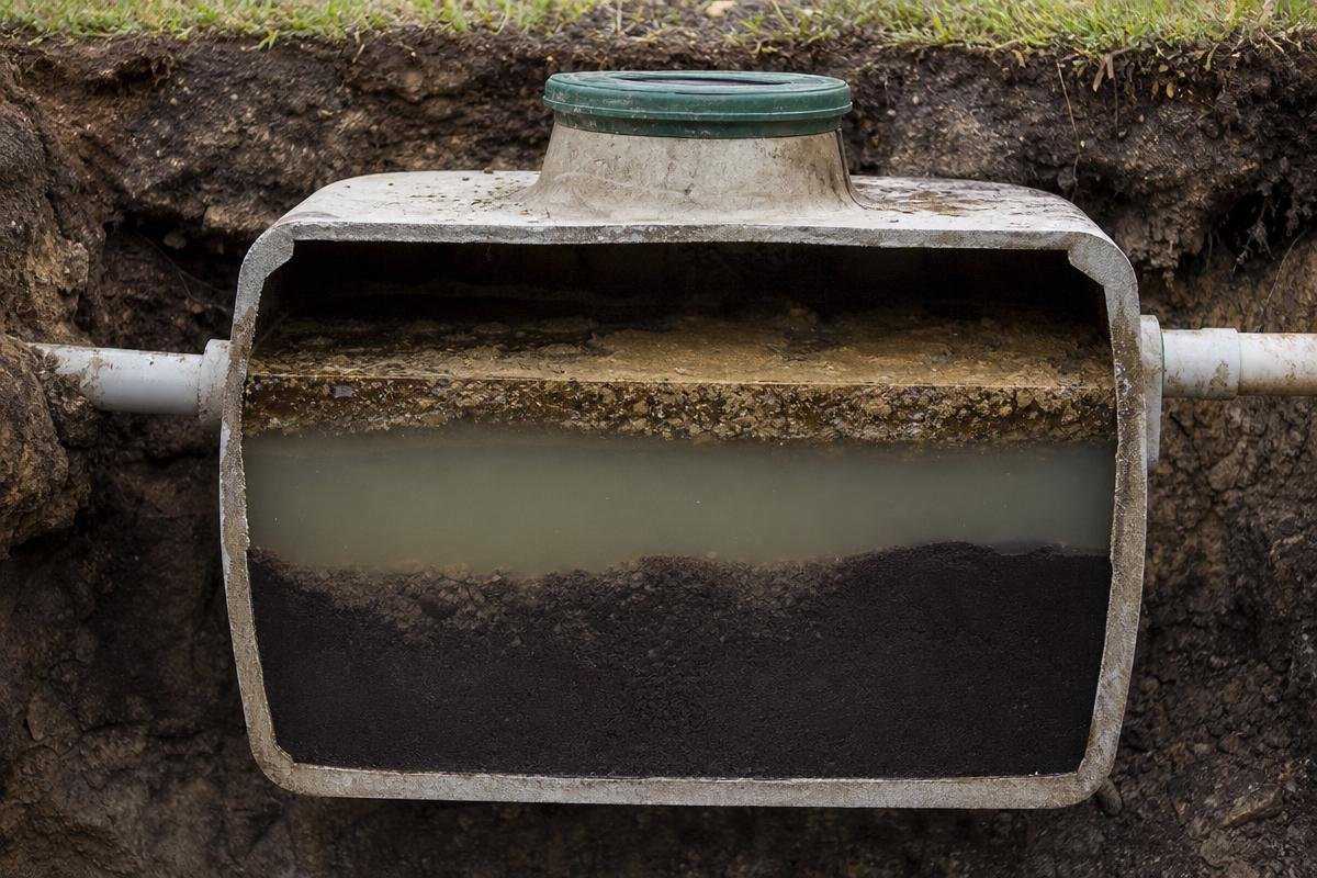 Septic tank cross-section showing scum, effluent, and sludge layers